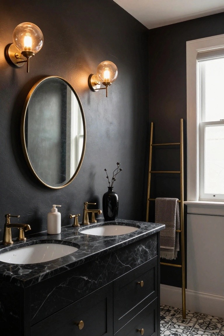 Dark-walled bathroom with black marble double vanity, two undermount sinks, brass faucets, large gold-framed round mirror, pair of brass globe wall sconces, gold ladder towel rack, and black-and-white patterned tile floor.