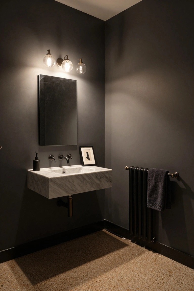 Modern bathroom corner featuring dark gray walls, a frameless mirror, floating white marble sink with black faucet, three wall-mounted globe pendant lights, soap dispenser, small framed artwork, and black towel radiator on the floor.