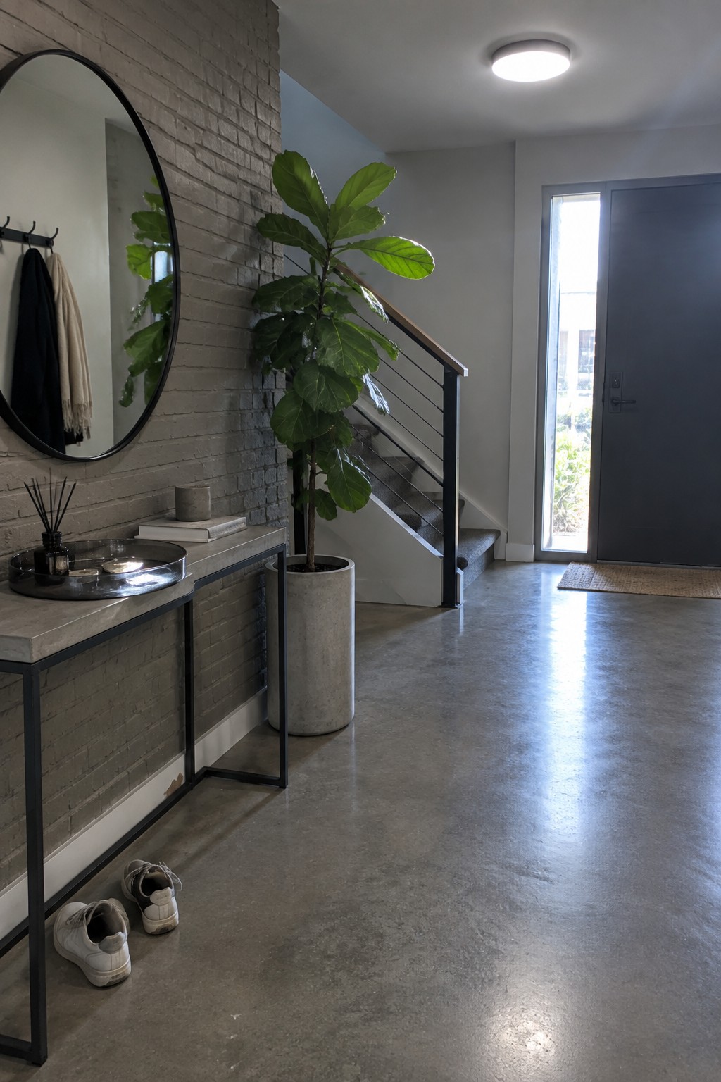 Modern entryway with round mirror on brick wall, fiddle-leaf fig, and concrete console