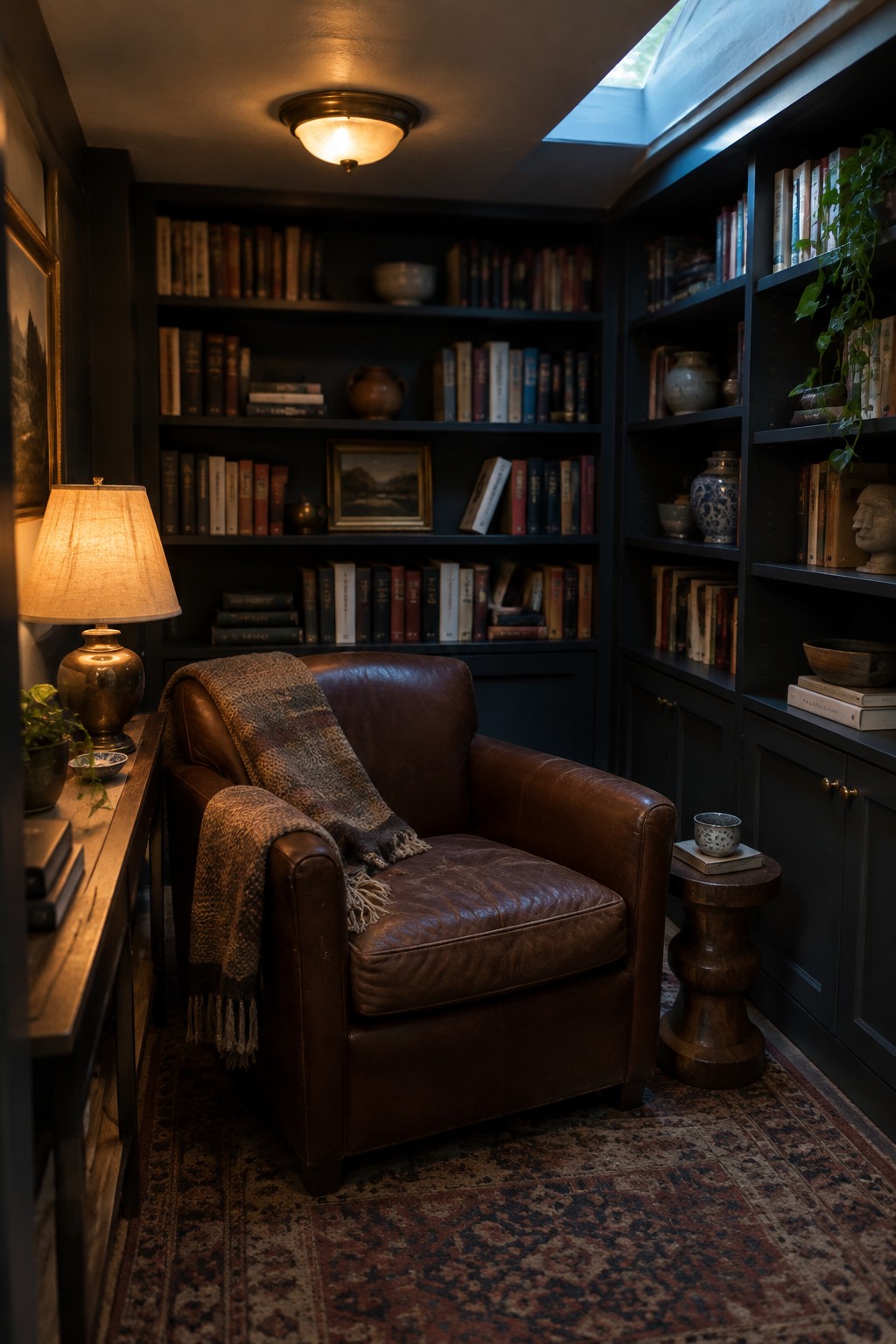 A small room with dark built-in bookshelves, a brown leather armchair with a patterned throw, a wooden side table, and a round flush mount ceiling light.