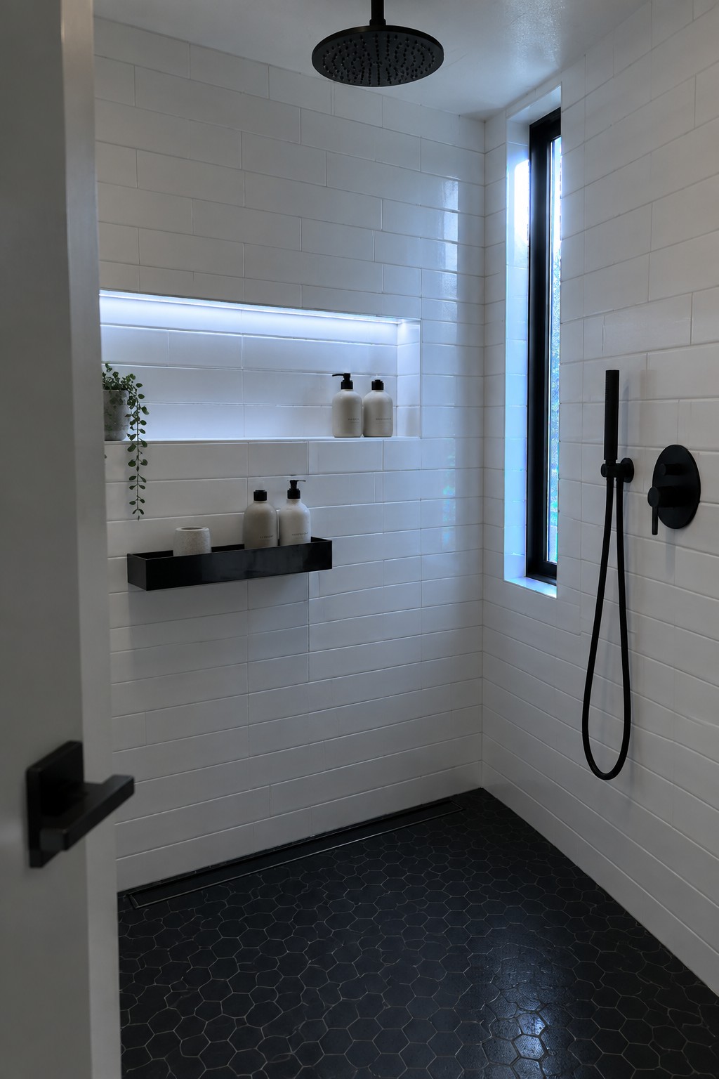 Modern shower with white subway tiles, black hex floor, and matte black fixtures.