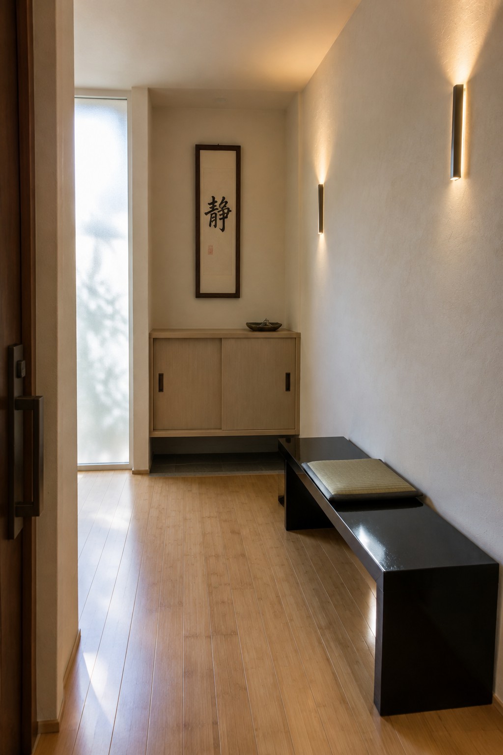 Minimalist Japanese hallway with light wood cabinet, calligraphy scroll, black bench, and wall sconces