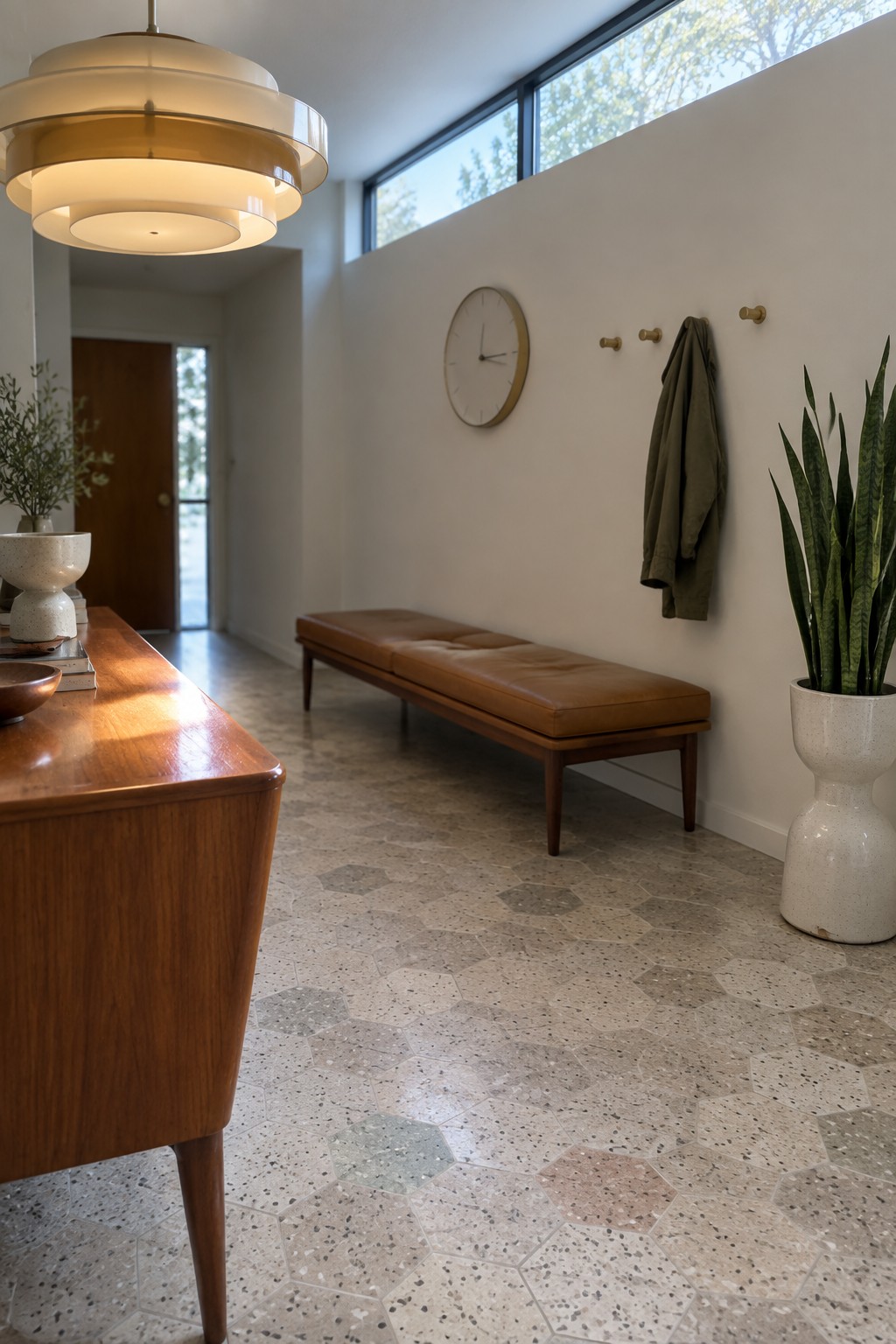 Mid-century modern entryway with leather bench, pendant light, clock, and snake plant.