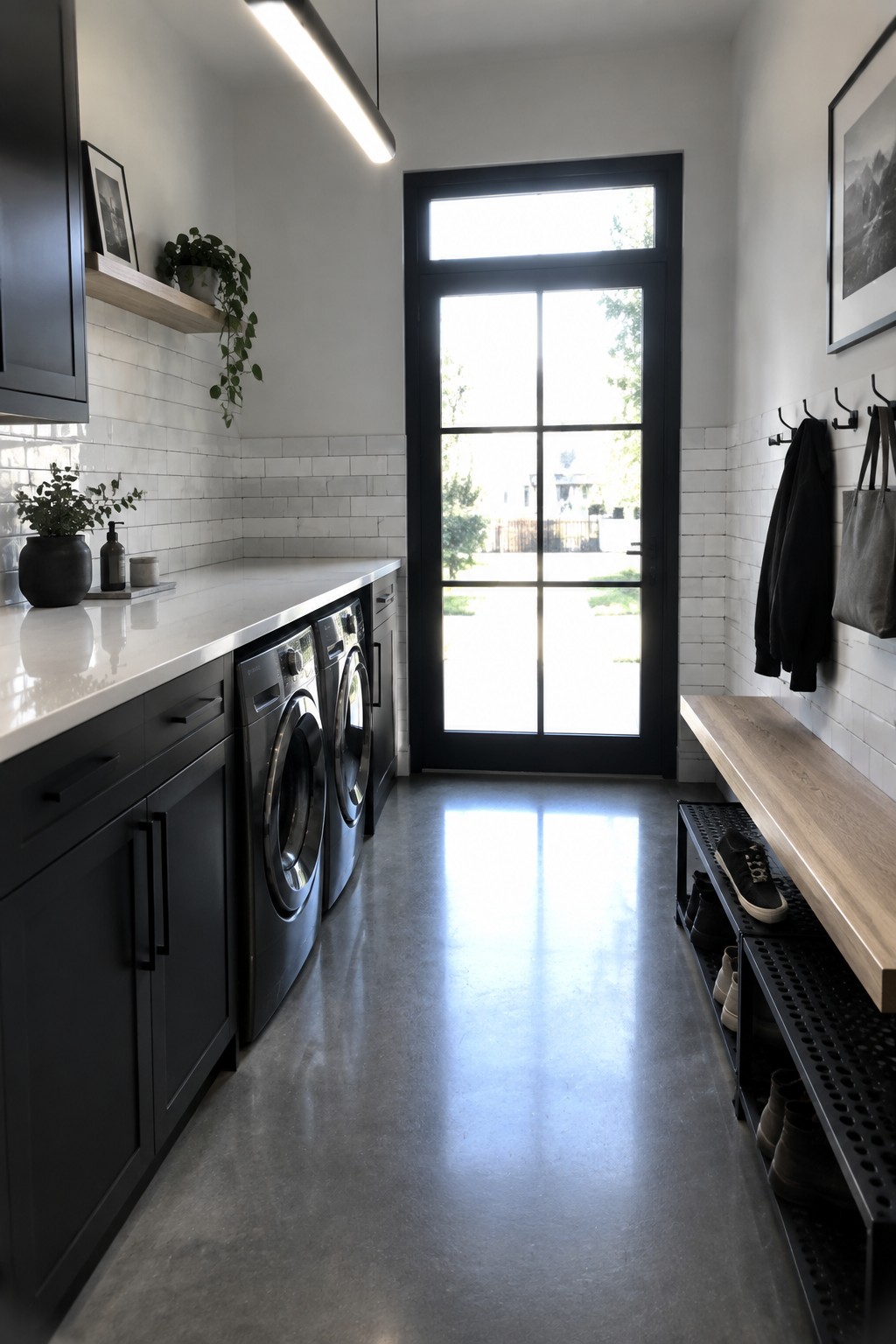 Modern laundry room with black cabinets, two washers, wooden bench, and glass door.