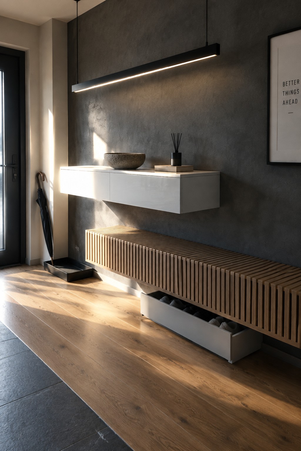 A modern foyer featuring a long black linear pendant light above a white floating console and a wooden slatted bench with an open shoe drawer.