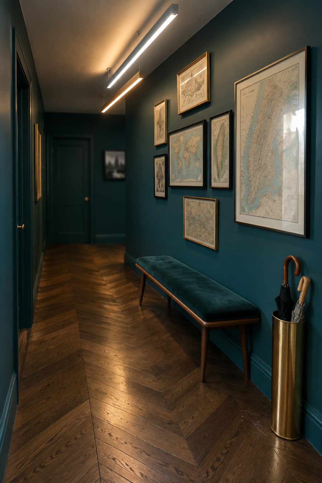 Teal hallway with herringbone floor, velvet bench, framed maps, and brass umbrella stand